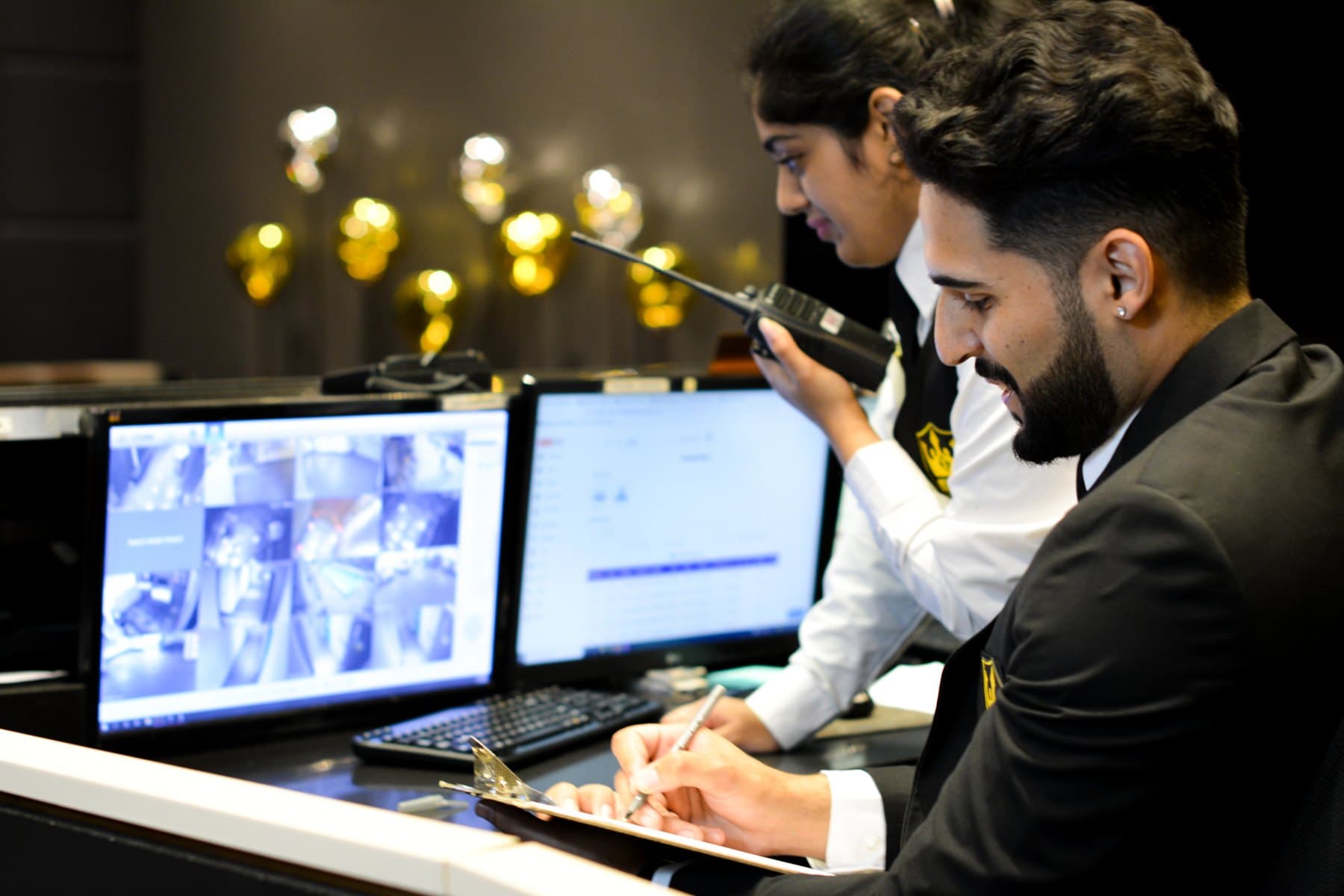 Royal concierge security officers at a condominium front desk with CCTV monitors